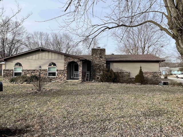 ranch-style home with a chimney and stone siding