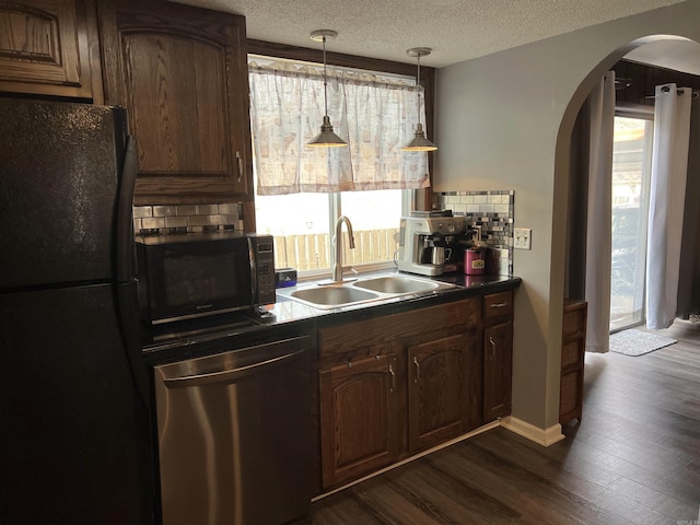 kitchen with a sink, arched walkways, backsplash, dark wood-style floors, and black appliances