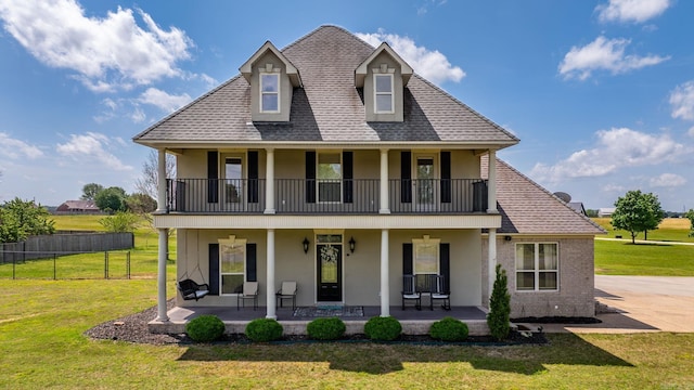 back of house with stucco siding, a yard, a porch, and a balcony