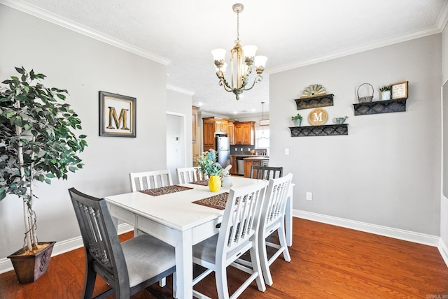 dining space with baseboards, ornamental molding, wood finished floors, and a notable chandelier