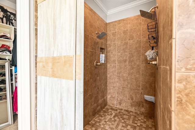 bathroom with ornamental molding, a tile shower, and a spacious closet
