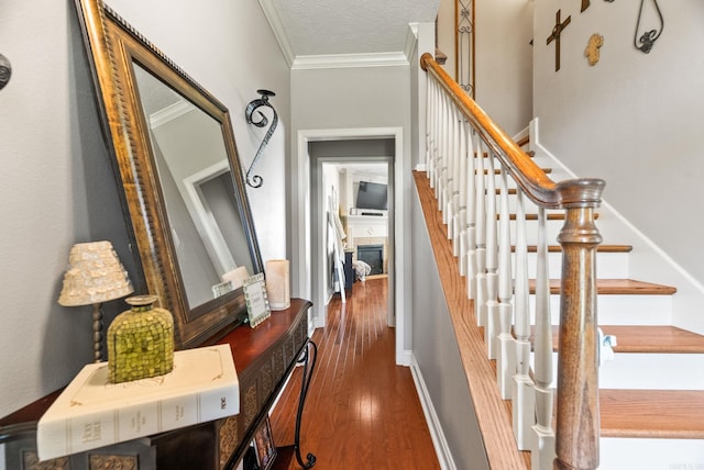 stairway with crown molding, a textured ceiling, and wood finished floors