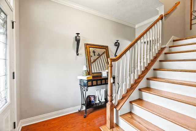 stairway featuring crown molding, baseboards, plenty of natural light, and wood finished floors