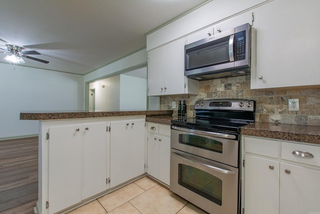 kitchen featuring white cabinets, a peninsula, appliances with stainless steel finishes, and decorative backsplash