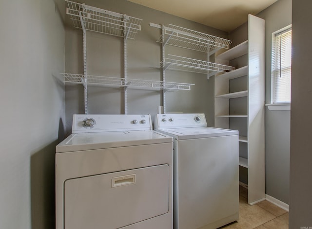 washroom with laundry area, baseboards, light tile patterned flooring, and washer and dryer