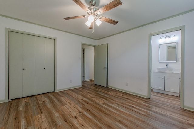 unfurnished bedroom with a sink, ensuite bathroom, a closet, and light wood-style flooring
