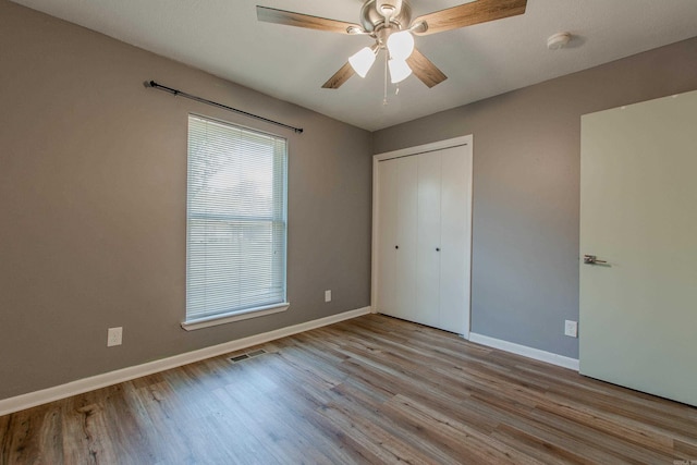 unfurnished bedroom with baseboards, a closet, and wood finished floors