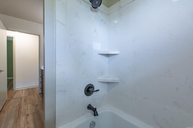 interior details with wood finished floors and shower / washtub combination