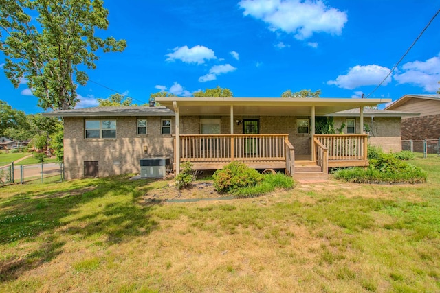 back of house with brick siding, fence, and a yard