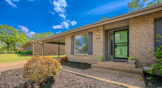 entrance to property with a yard and brick siding