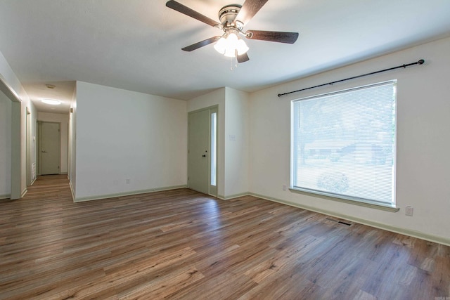 unfurnished room featuring baseboards, ceiling fan, wood finished floors, and visible vents