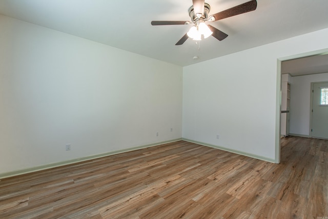 spare room featuring light wood-style floors, baseboards, and a ceiling fan