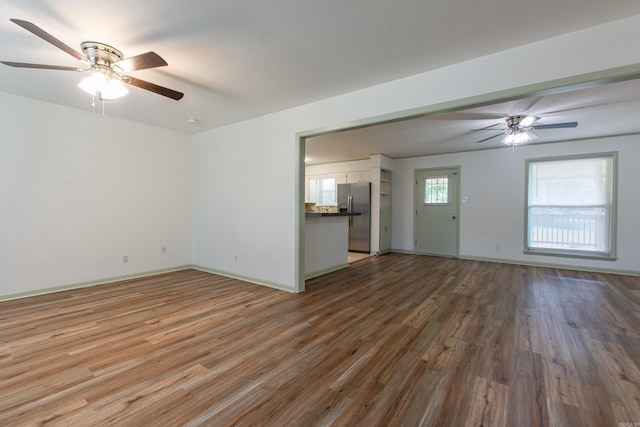 unfurnished living room featuring baseboards, ceiling fan, and wood finished floors