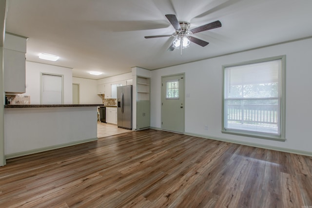 unfurnished living room featuring baseboards, ceiling fan, and light wood-style flooring