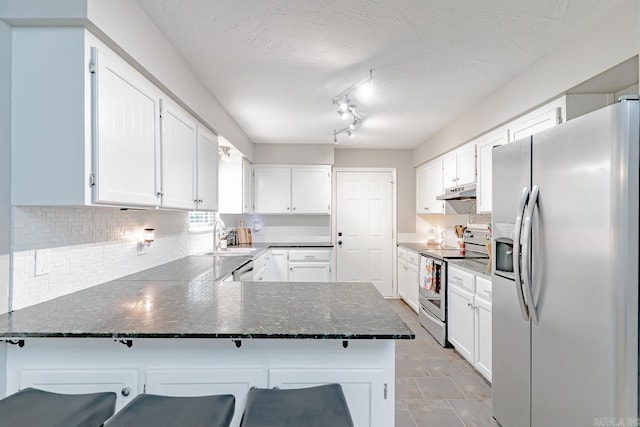 1321 W Front St, Heber Springs, AR 72543 - kitchen with backsplash, white cabinets, a peninsula, under cabinet range hood, and stainless steel appliances