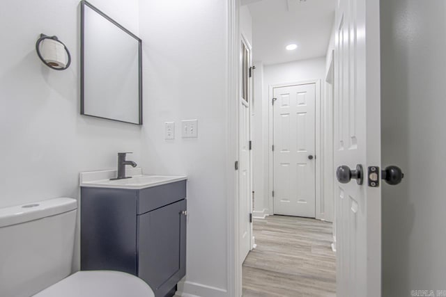 bathroom with vanity, toilet, recessed lighting, baseboards, and wood finished floors