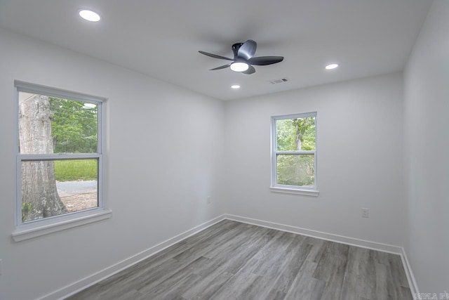 empty room with a ceiling fan, baseboards, visible vents, and wood finished floors