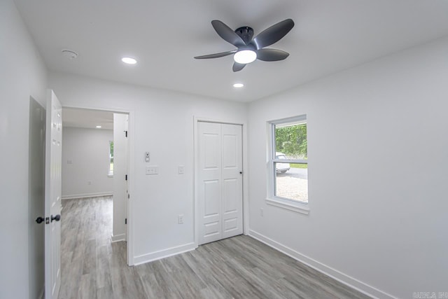 unfurnished bedroom with baseboards, a closet, recessed lighting, and wood finished floors