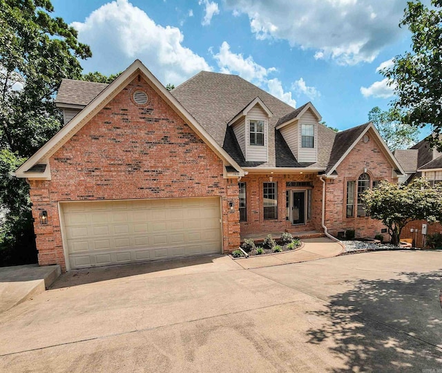 view of front of house with brick siding, driveway, and roof with shingles