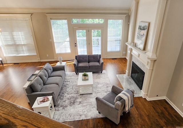 living area with visible vents, ornamental molding, wood finished floors, baseboards, and a high end fireplace