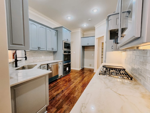 kitchen featuring crown molding, tasteful backsplash, light stone counters, a sink, and appliances with stainless steel finishes