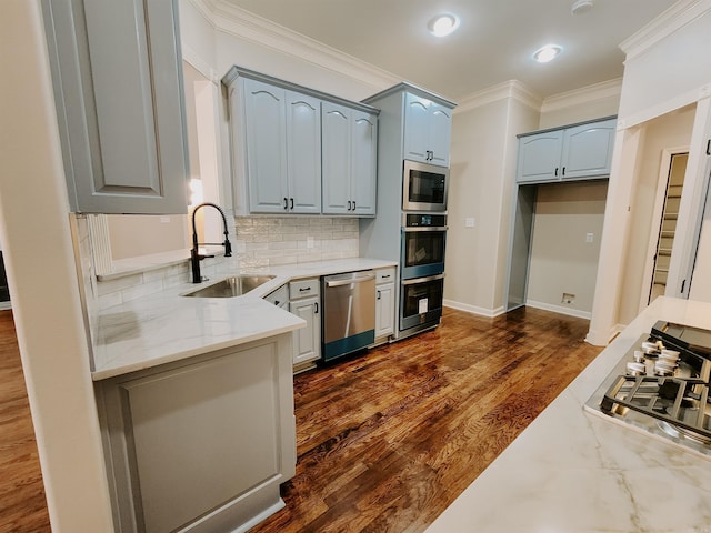 kitchen featuring crown molding, appliances with stainless steel finishes, tasteful backsplash, a sink, and light stone counters