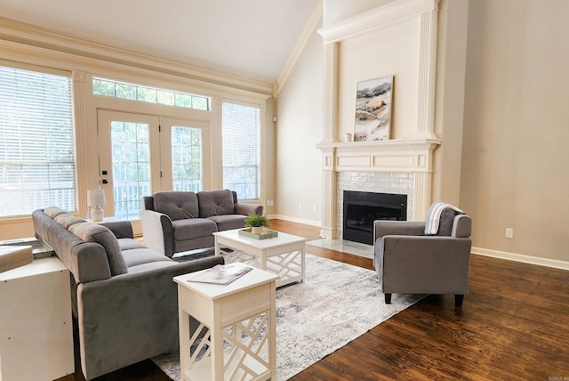 living room featuring crown molding, vaulted ceiling, dark wood finished floors, a brick fireplace, and baseboards