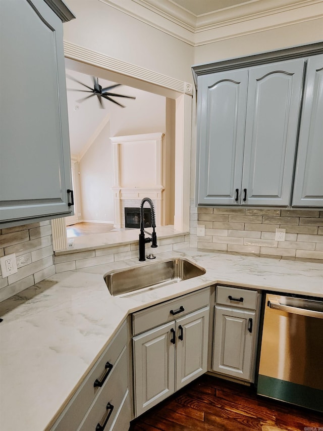 kitchen featuring light stone countertops, a sink, dishwasher, backsplash, and ornamental molding