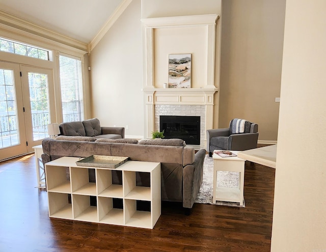 living room with crown molding, vaulted ceiling, a brick fireplace, and dark wood finished floors