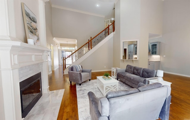 living room with stairway, baseboards, crown molding, and a towering ceiling