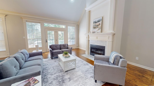 living room with baseboards, a fireplace with flush hearth, ornamental molding, and lofted ceiling