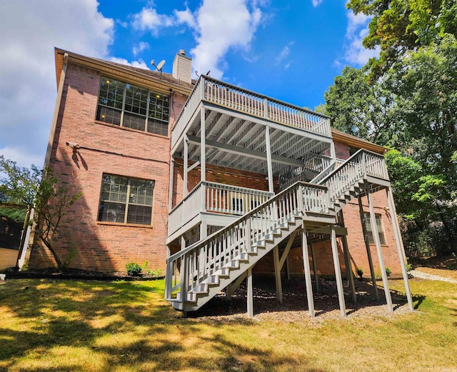 rear view of property with stairs, a chimney, a yard, and brick siding