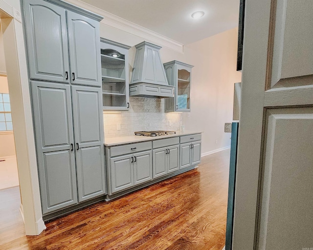 kitchen featuring glass insert cabinets, gray cabinets, custom range hood, and dark wood-style flooring
