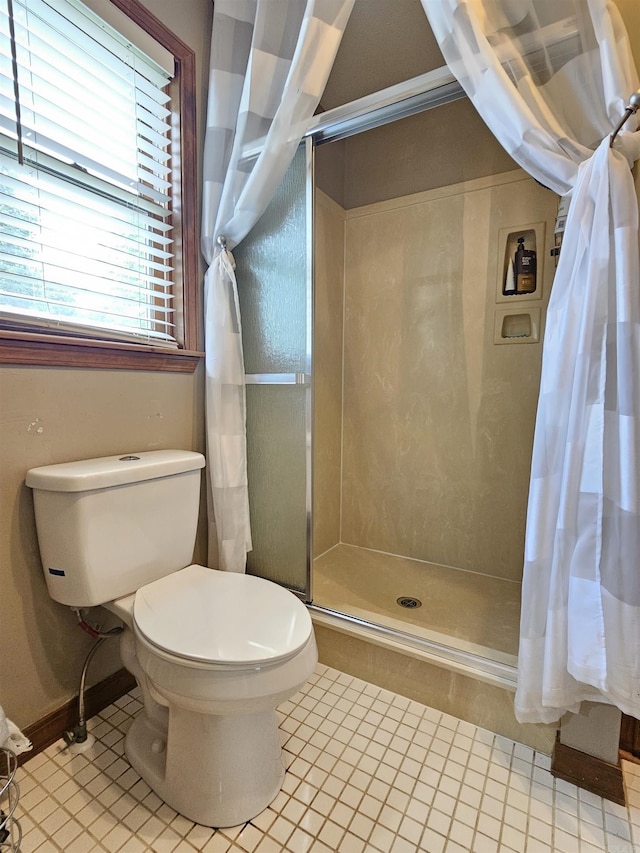 bathroom with tile patterned floors, baseboards, a shower stall, and toilet