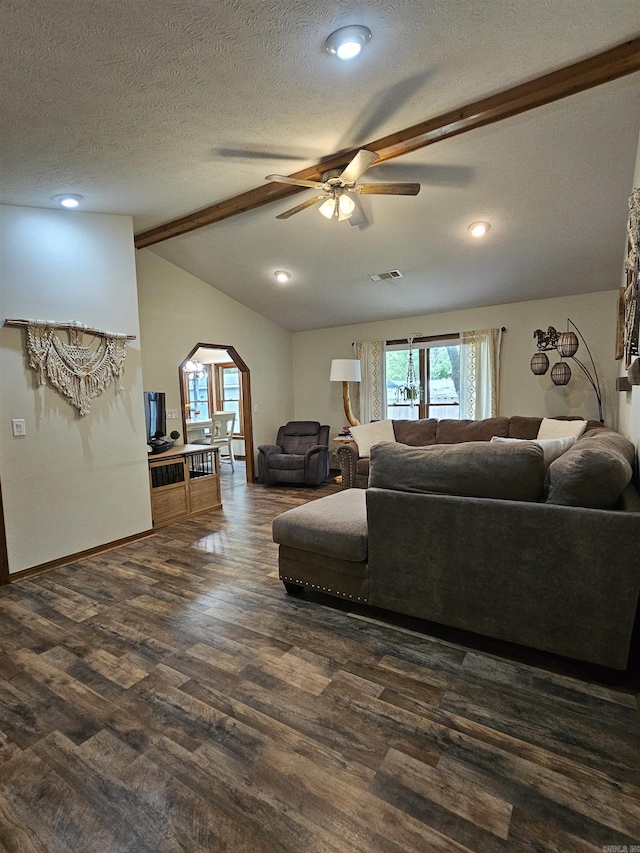 living room with ceiling fan, visible vents, arched walkways, dark wood-style floors, and vaulted ceiling with beams