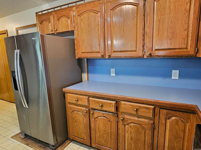 kitchen featuring light countertops, stainless steel refrigerator with ice dispenser, and brown cabinetry