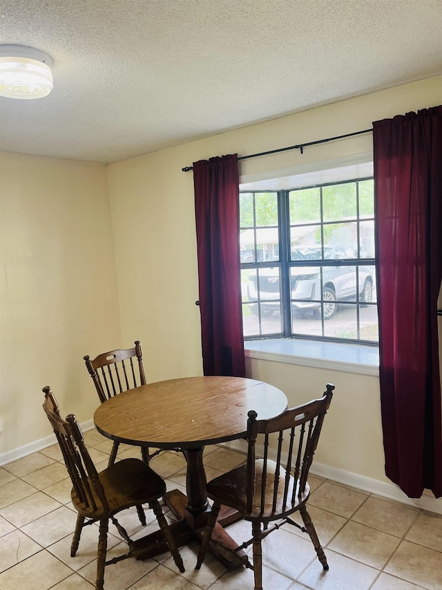 dining space featuring baseboards, a textured ceiling, and light tile patterned flooring
