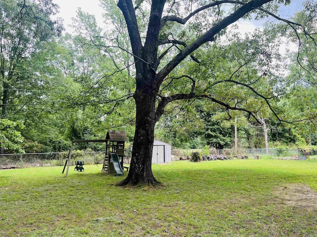view of yard with a fenced backyard, an outbuilding, a shed, and a playground