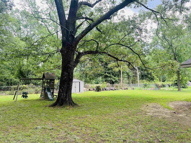 view of yard featuring a fenced backyard, an outbuilding, a shed, and a playground