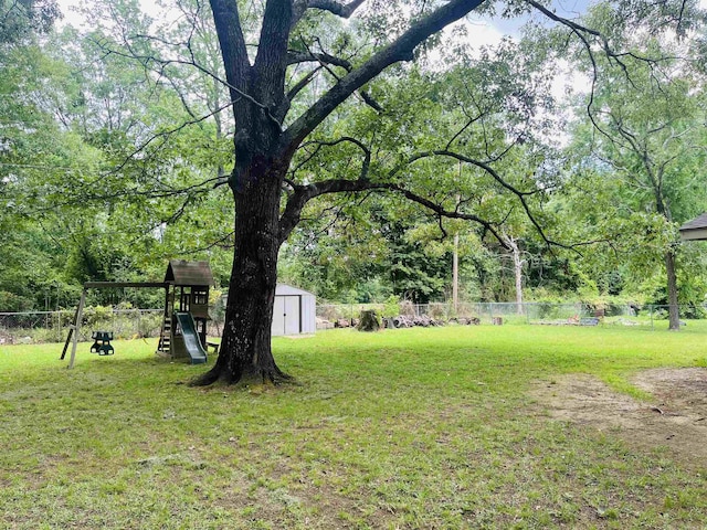 view of yard with a storage shed, fence, an outdoor structure, and a playground