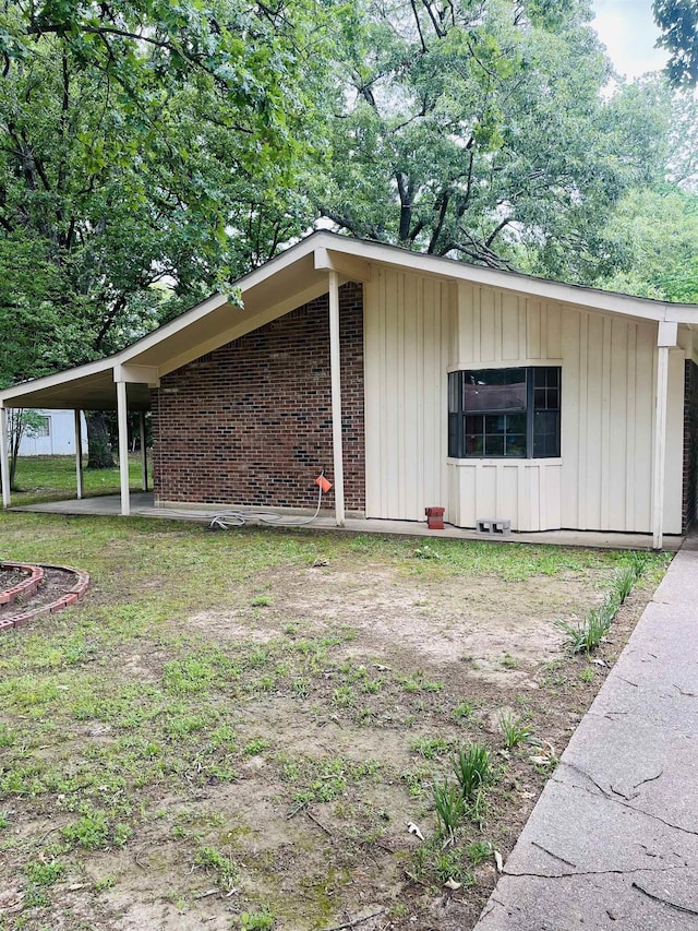 view of home's exterior with board and batten siding, brick siding, and a carport