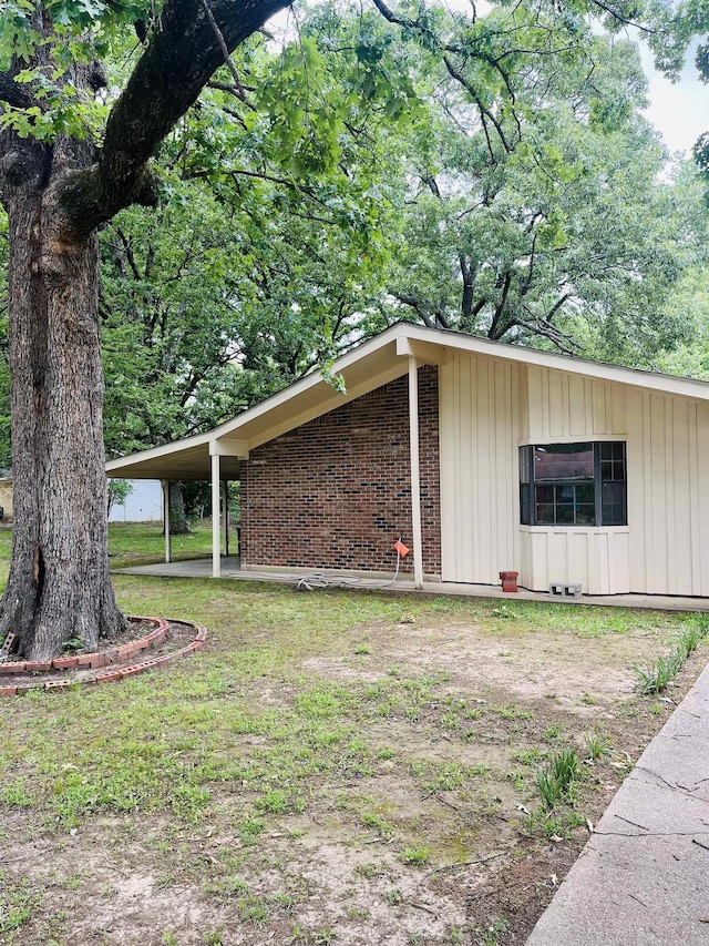 view of side of home featuring board and batten siding, brick siding, and a carport
