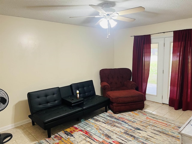 sitting room featuring tile patterned flooring, a textured ceiling, ceiling fan, and baseboards