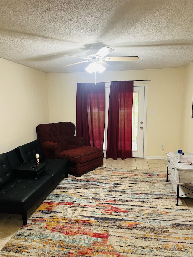tiled living area with a ceiling fan and a textured ceiling