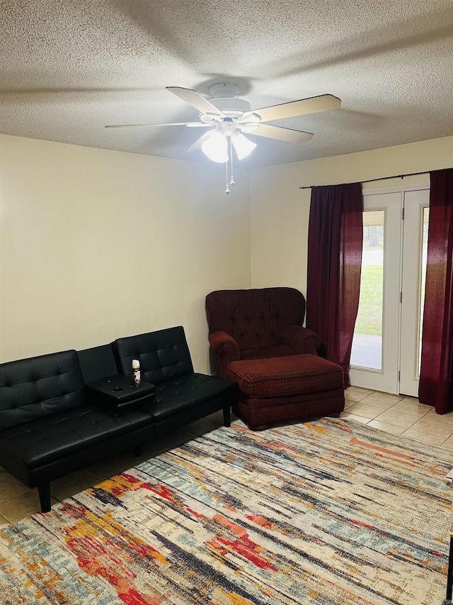 living area with a textured ceiling, ceiling fan, and tile patterned floors