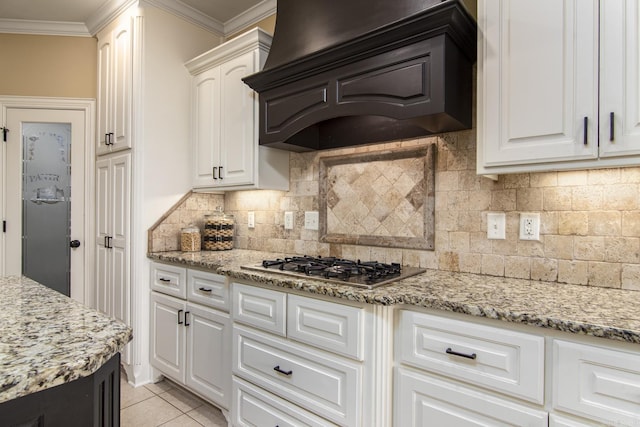 9241 Johnson Dr, Sherwood, AR 72120 - kitchen with decorative backsplash, crown molding, stainless steel gas cooktop, light stone counters, and custom exhaust hood