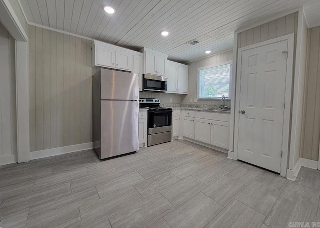 kitchen with white cabinets, appliances with stainless steel finishes, wood walls, visible vents, and wood ceiling