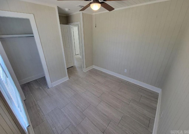 unfurnished bedroom featuring wooden walls, wood tiled floor, ceiling fan, and visible vents