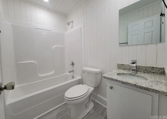 full bathroom with toilet, wood walls, washtub / shower combination, and vanity