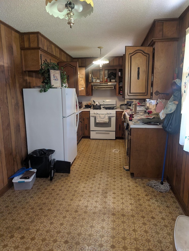 kitchen with a textured ceiling, wood walls, light countertops, light floors, and white appliances